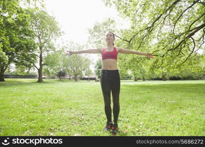 Full length of young woman listening to music while exercising in park