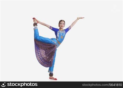 Full length of young woman performing Bharat Natyam dance over white background