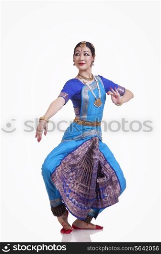 Full length of young woman performing Bharatanatyam over white background
