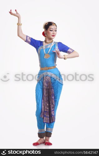 Full length of young woman performing Bharatanatyam over white background