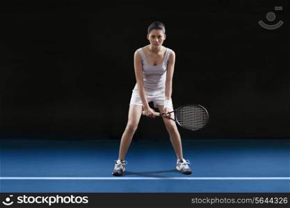Full length of young woman playing tennis at court