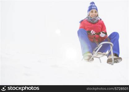 Full length of young woman sledging in snow