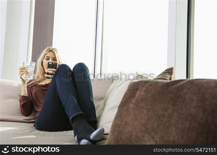 Full length of young woman text messaging at home