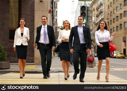 Full length portrait of a young Five successful business people crossing the street in the city center