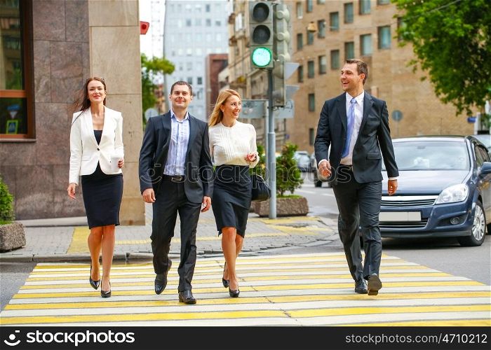 Full length portrait of a young four successful business people crossing the street in the city center