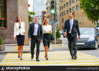 Full length portrait of a young four successful business people crossing the street in the city center