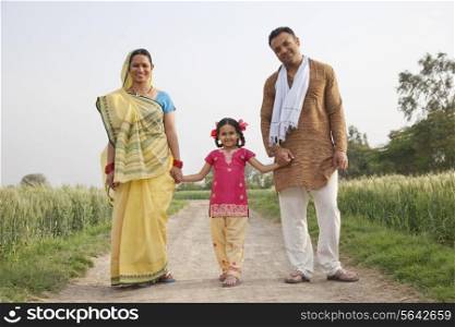 Full length portrait of a young girl with her family walking on rural road