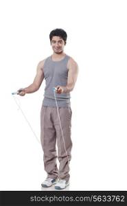 Full length portrait of a young man with skipping rope over white background