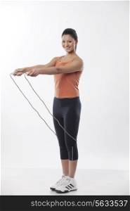 Full length portrait of a young woman with jump rope over white background