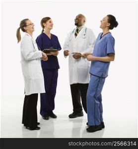 Full-length portrait of African-American man and Caucasian women medical healthcare workers in uniforms laughing standing against white background.