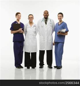 Full-length portrait of African-American man and Caucasian women medical healthcare workers smiling in uniforms standing against white background.