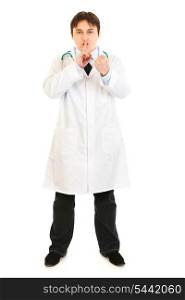 Full length portrait of angry medical doctor with finger at mouth and threaten with fist isolated on white&#xA;
