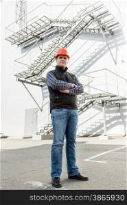Full length portrait of architect posing against metal construction