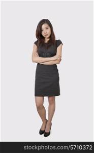 Full length portrait of beautiful young businesswoman standing arms crossed over white background