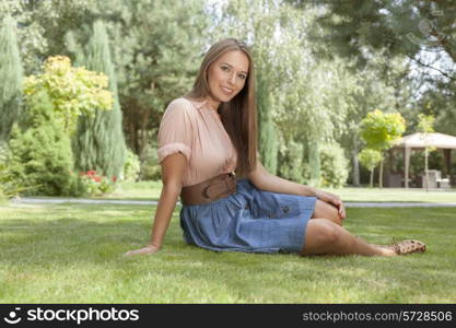 Full length portrait of beautiful young woman in casuals relaxing in park