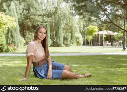 Full length portrait of beautiful young woman relaxing in park