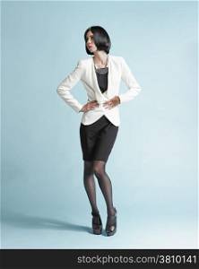 Full length portrait of beautiful young woman wearing a white jacket and skirt - studio shot
