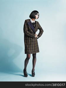 Full length portrait of beautiful young woman wearing an overcoat - studio shot