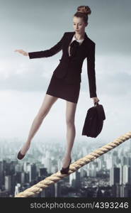 full-length portrait of blonde business woman with dark suit and working bag in unstable balance &#xA;