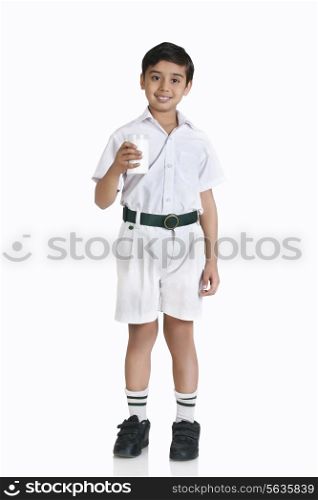 Full length portrait of boy in school uniform holding milk over white background