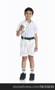 Full length portrait of boy in school uniform holding milk over white background