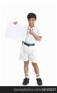 Full length portrait of boy in school uniform showing blank placard against white background