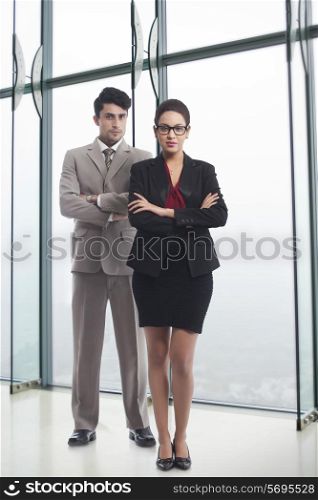 Full length portrait of business people standing arms crossed in office