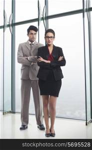 Full length portrait of business people standing arms crossed in office