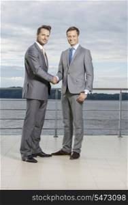 Full length portrait of businessmen shaking hands on terrace