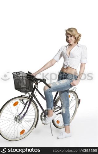 full-length portrait of casual blonde girl with jeans and shirt posing near bicycle and smiling