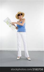 Full length portrait of Caucasian woman holding map and pointing to location.