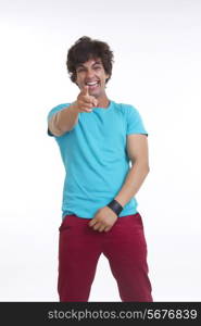 Full length portrait of cheerful young man pointing at you over white background