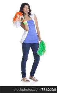 Full length portrait of cheerful young woman in casuals holding Indian tricolor pom poms over white background