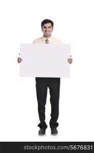Full length portrait of confident businessman holding blank placard over white background