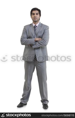 Full length portrait of confident businessman with arms crossed standing against white background