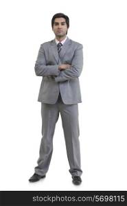 Full length portrait of confident businessman with arms crossed standing against white background