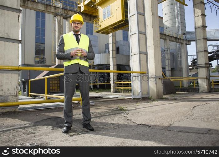 Full length portrait of confident young male architect standing outside industry