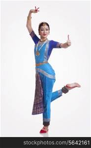 Full length portrait of confident young woman performing Bharatanatyam over white background