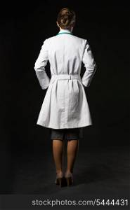 Full length portrait of doctor woman isolated on black. rear view