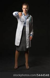 Full length portrait of doctor woman showing thumbs down on black background