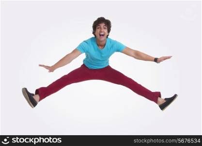 Full length portrait of excited young man jumping over white background