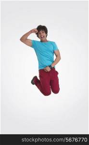 Full length portrait of excited young man jumping over white background