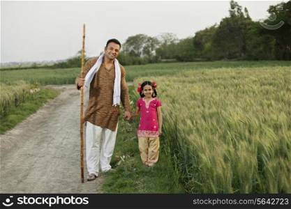 Full length portrait of father and daughter standing together in wheat field