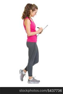 Full length portrait of fitness trainer writing in clipboard