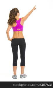 Full length portrait of fitness young woman pointing on copy space . rear view