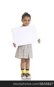 Full length portrait of girl in school uniform holding blank placard against white background