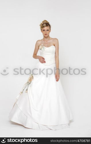 Full length portrait of gorgeous bride wearing wedding dress over grey background