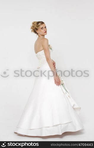 Full length portrait of gorgeous bride wearing wedding dress over grey background