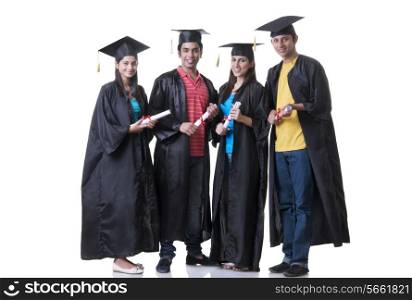 Full length portrait of graduate students holding diplomas against white background