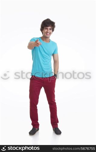 Full length portrait of handsome young man pointing at you over white background